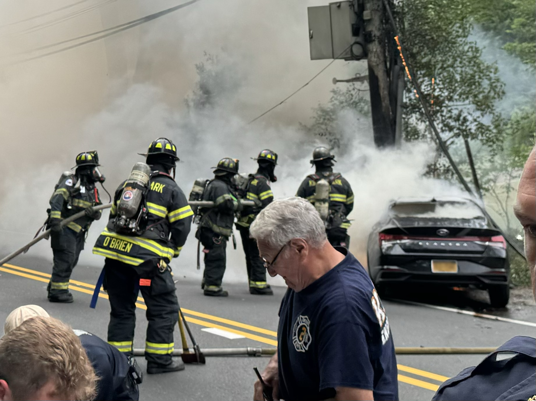 Members of the Kings Park Fire Department extinguish a car fire on Bread and Cheese Hollow Road in Fort Salonga yesterday evening. The driver, who was trapped inside, was rescued from her car by three good Samaritans seconds before the car became engulfed in flames. 