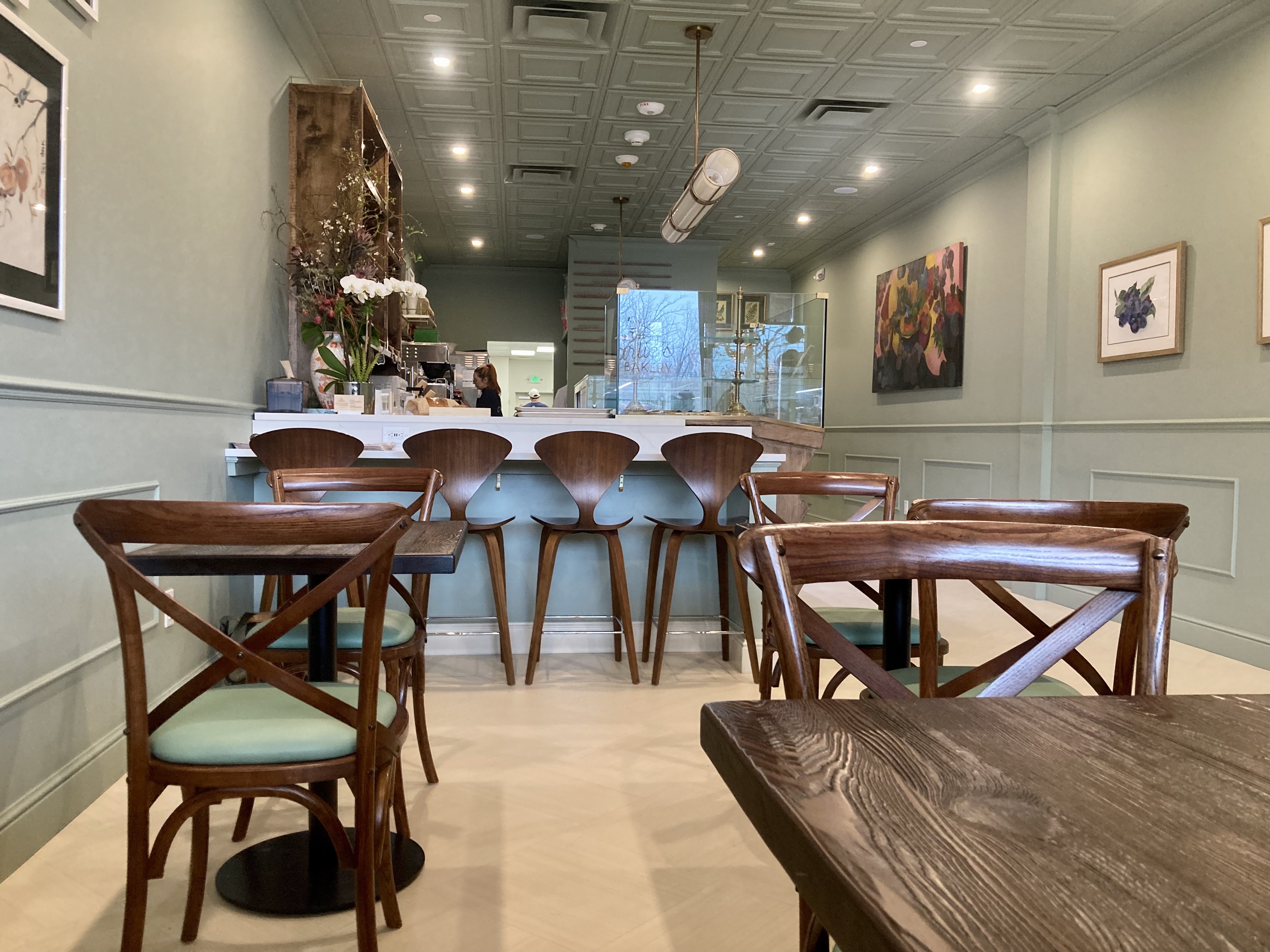 The interior of Charlie’s Bakery in Northport features banquette and bar seating, tables for two and artwork by owner Casey Sandler’s mom, Muriel. 