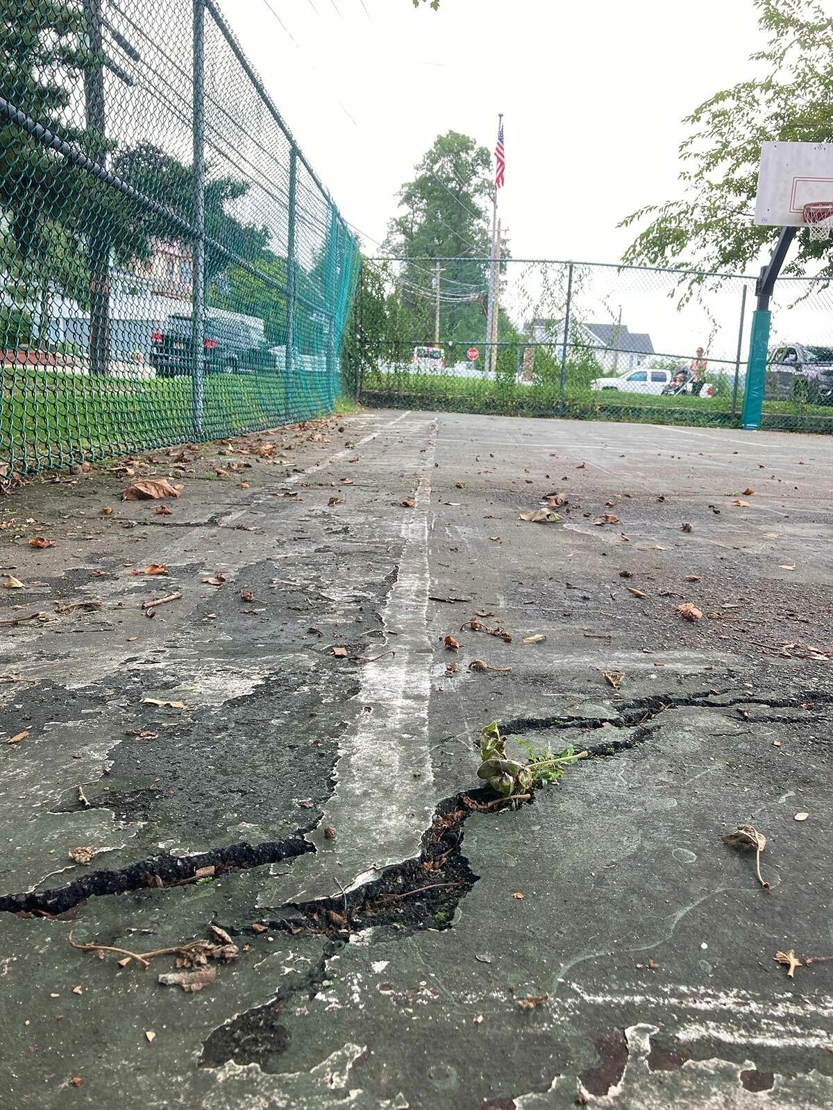A closeup of cracks in the asphalt at the existing basketball court in Cow Harbor Park in Northport Village.