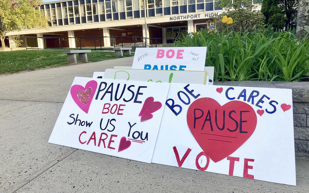 Signs from the rally urging board members to “press pause” on the district’s reorganization plan.