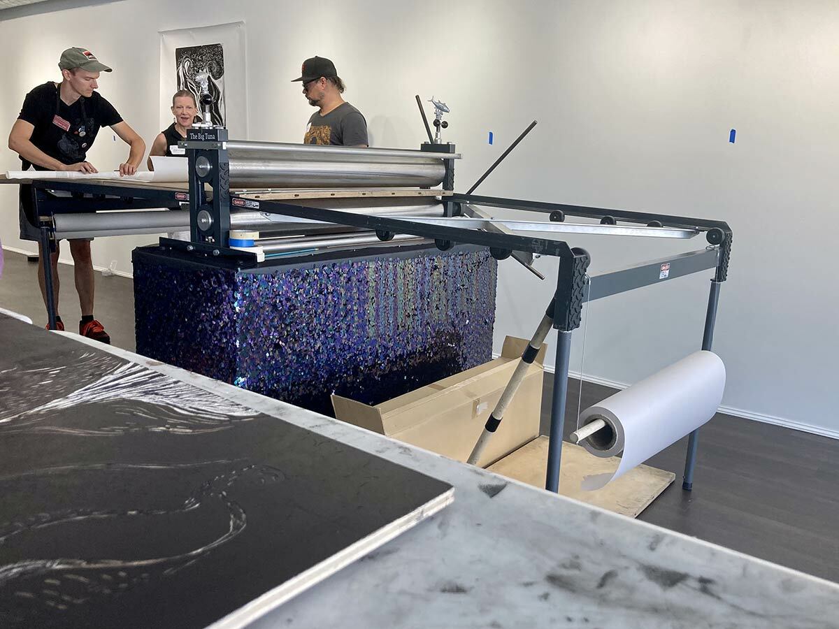 An ink-coated woodblock after going through The Big Tuna, a large-scale press taking center stage at the BIG INK event at The Firefly Artists’ new location in Northport Village this weekend. Pictured, from left, are BIG INK founder Lyell Castonguay with artists Constance Sloggatt Wolf and Troy Hahn.