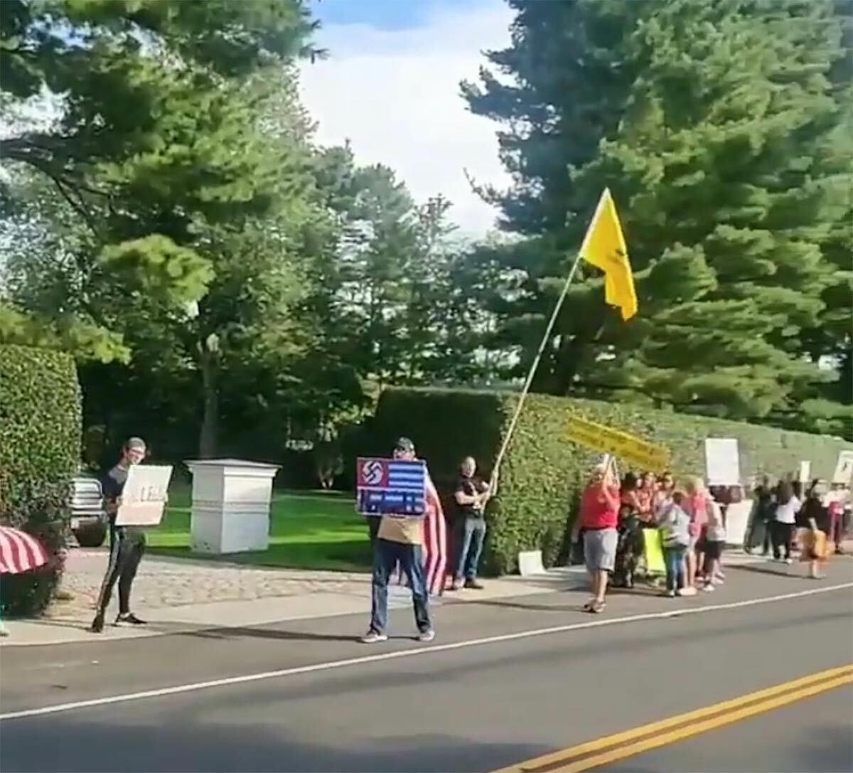 An image of a protestor, holding a sign with a swastika on it, in front of Northwell Health CEO Michael Dowling&#39;s house from this past weekend. Photo via Instagram.