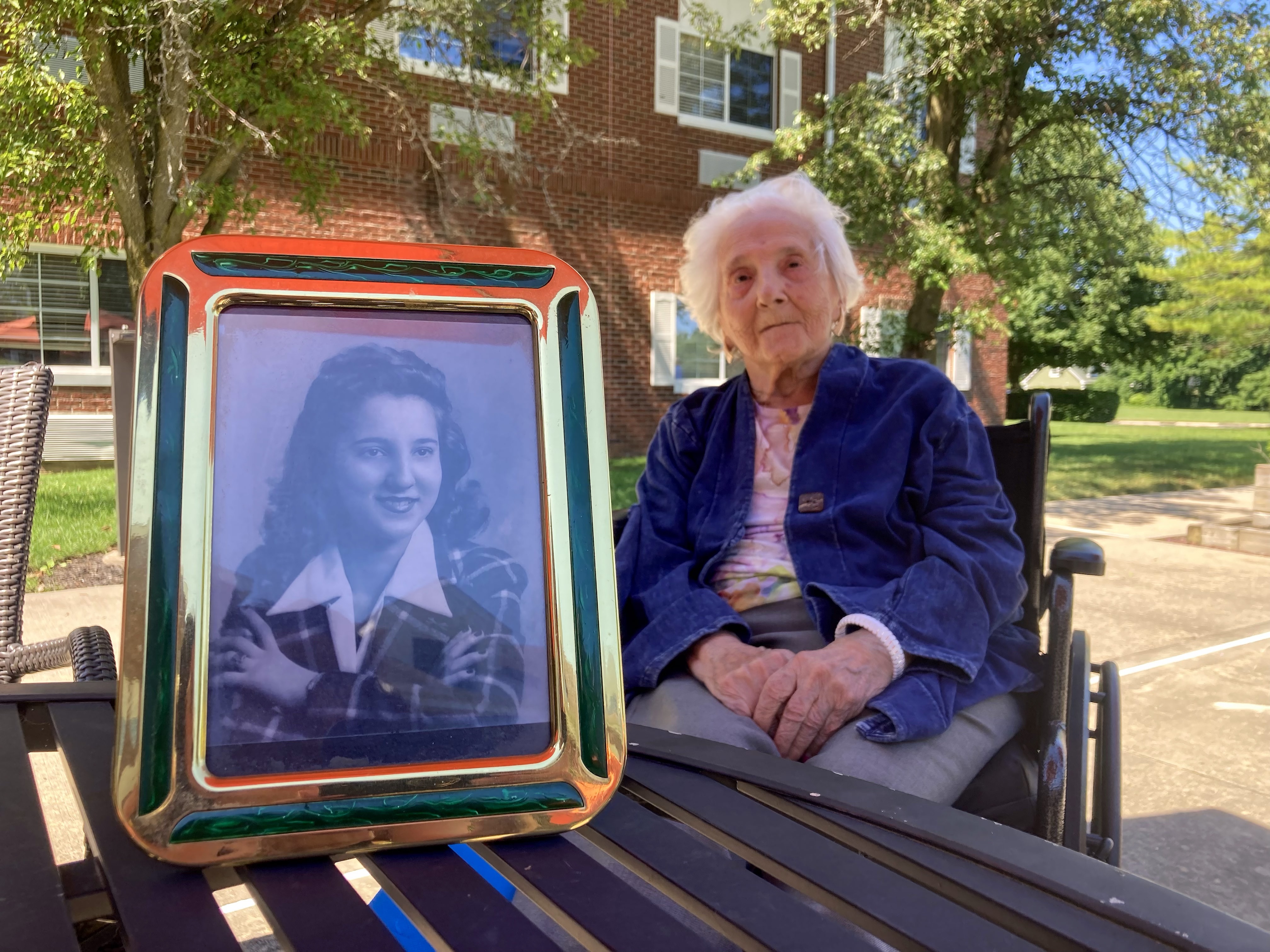 Helen Gabay, who recently turned 100 years old, in the courtyard of Atria Senior Living in East Northport. A photo of Helen in her younger years is in the foreground. 