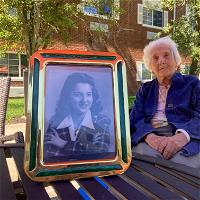 Helen Gabay, who recently turned 100 years old, in the courtyard of Atria Senior Living in East Northport. A photo of Helen in her younger years is in the foreground. 