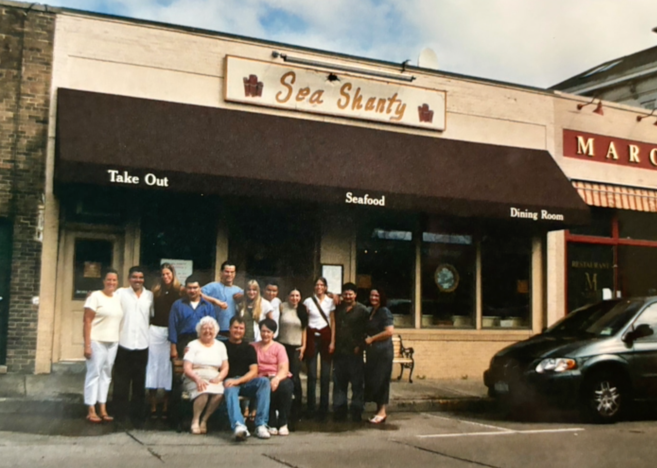 Restaurant owner Marie José Blazej (seated, left) and staff in front of the Sea Shanty on Woodbine Avenue in Northport Village. Blazej passed away last month, on March 21. Photo via the Gately Funeral Home website. 