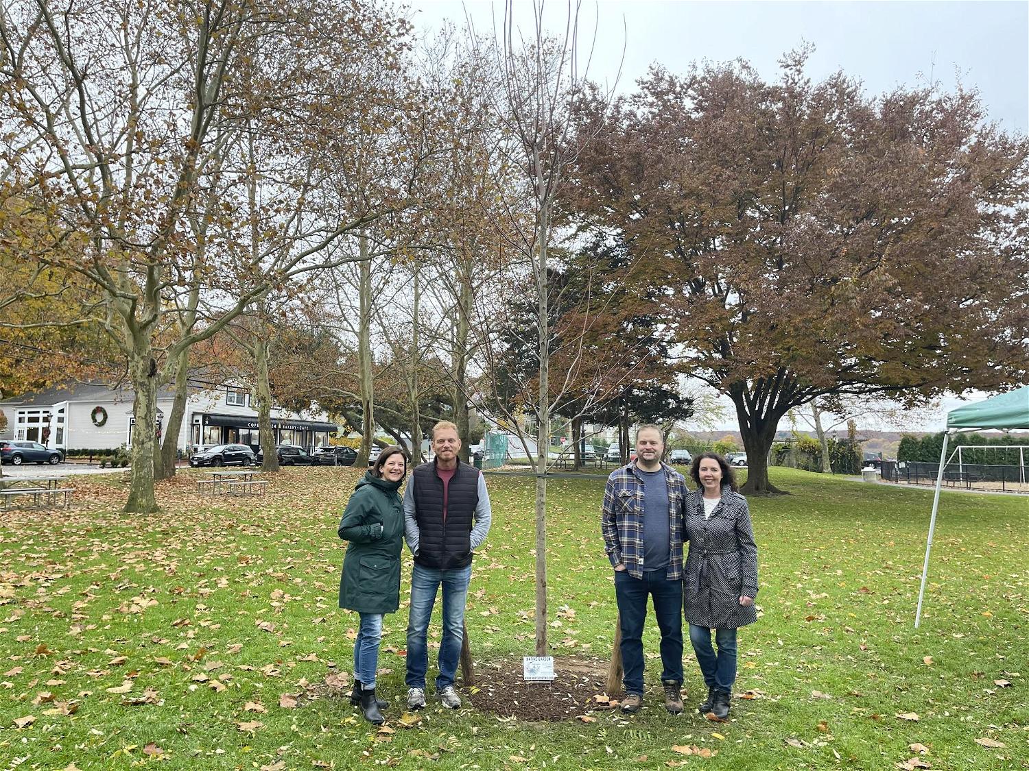 One of two donated native red maple trees in Cow Harbor Park. The 14-inch caliper trees are 18 feet in height and contribute to the park’s biodiversity. From left, Nicole Tamaro, Robb Smith, Matt Gorman and Barbara Bolen. 