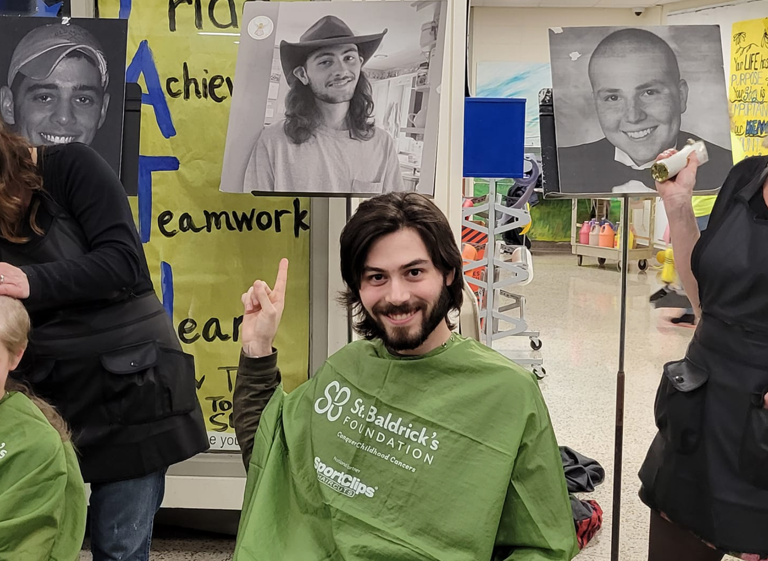 Noah Paquet at the March 2023 St. Baldrick’s event at Northport High School. His brother Caleb, who passed away from cancer in 2017, is pictured in the photo behind him.